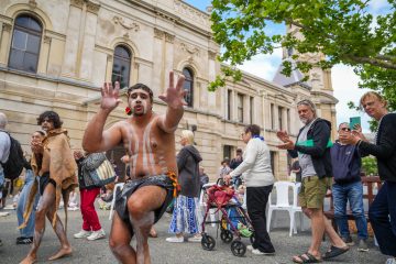 A man in tribal attire dances before an audience, showcasing cultural expression.
