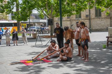 A diverse group seated on the ground, conversing and enjoying each other's company.