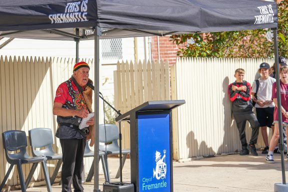 An elderly man speaks at a podium with a 