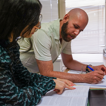 Two people looking at paperwork on a desk.